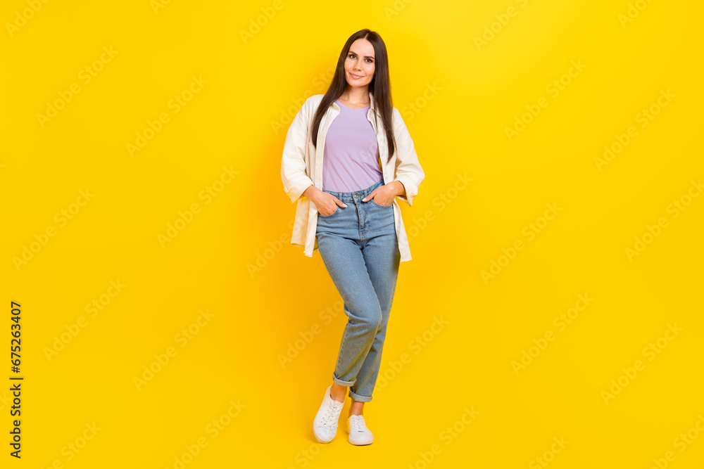 Full length photo of pleasant adorable woman dressed white jacket jeans holding palms in pockets isolated on yellow color background Full length photo of pleasant adorable woman dressed white jacket jeans holding palms in pockets isolated on yellow color background