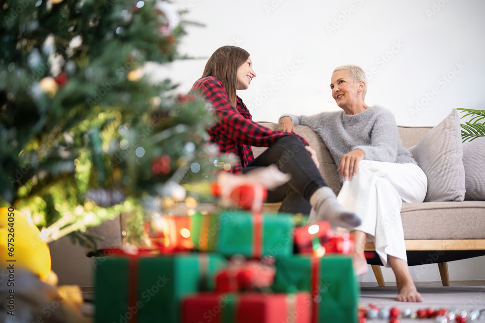Senior woman with adult daughter enjoying time at home on Christmas eve Senior woman with adult daughter enjoying time at home on Christmas eve