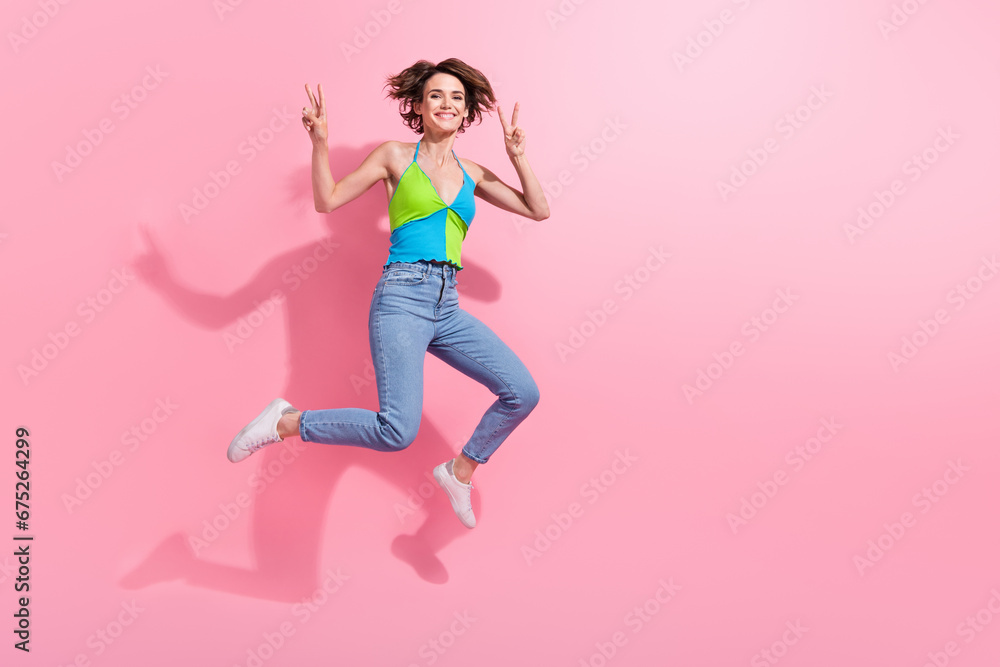 Full length photo of crazy jumper youngster funky woman showing double v sign fingers on summer party isolated over pink color background Full length photo of crazy jumper youngster funky woman showing double v sign fingers on summer party isolated over pink color background