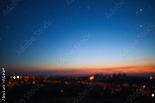 Out of focus image of crescent young Moon and planets on colorful sky.