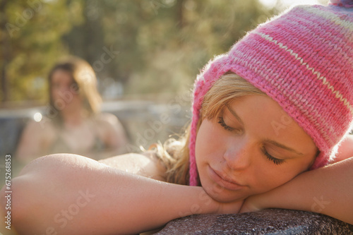 Young woman resting on the edge of a hot tub with her eyes closed
 photo