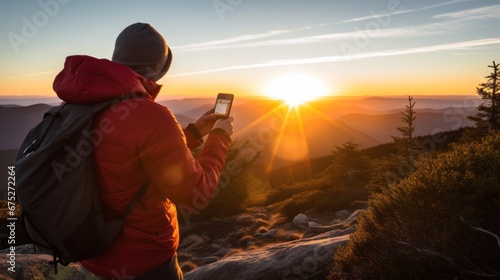 attractive active sport traveller in jacket hand using smartphone taking photo of sunrise on a mountain forest peak nature environment landscape male hiking take photo on top of hill morning photo