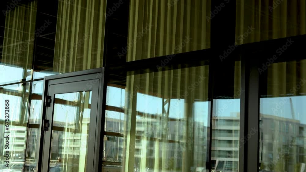 Interior view through a glass curtain wall with golden reflections, overlooking other buildings. Interior view through a glass curtain wall with golden reflections, overlooking other buildings.