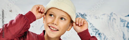 jolly little boy in stylish attire putting on his trendy beanie hat, fashion concept, banner