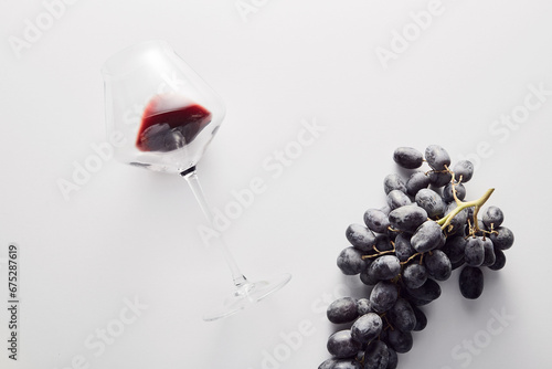 Wineglass with red wine, bunch of dark-colored grape. photo