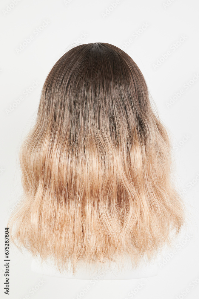 Natural looking blonde fair wig on white mannequin head. Middle length hair cut on the plastic wig holder isolated on white background, back view Natural looking blonde fair wig on white mannequin head. Middle length hair cut on the plastic wig holder isolated on white background, back view