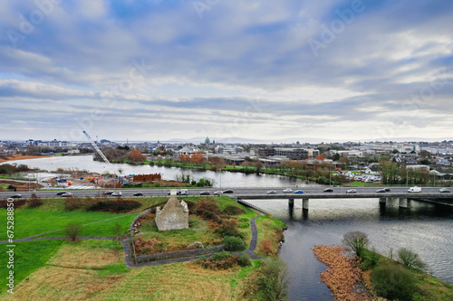 Aerial view on Terryland Forest Park, Quincentennial Bridge in Galway city, Ireland. Ocean and Burren area in the background. Old water work building in foreground. Cloudy sky.