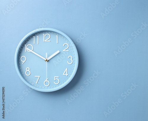 wall clock on blue paper background with copy space