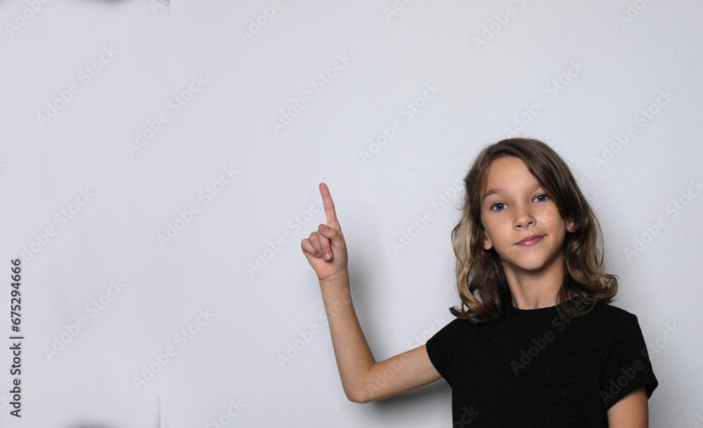 Schoolgirl points her finger up. The concept of attracting attention to interesting things. Interesting funny facial expressions Schoolgirl points her finger up. The concept of attracting attention to interesting things. Interesting funny facial expressions