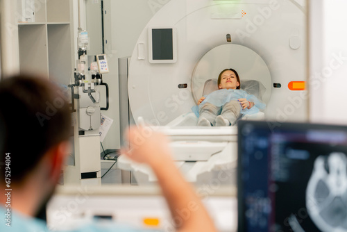 A girl lies on an MRI machine before examining her body and the radiologist gives command to her to prepare for diagnosis