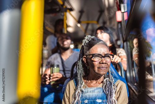 Senior woman with afro hairstyle looking out the bus window. © Brastock Images