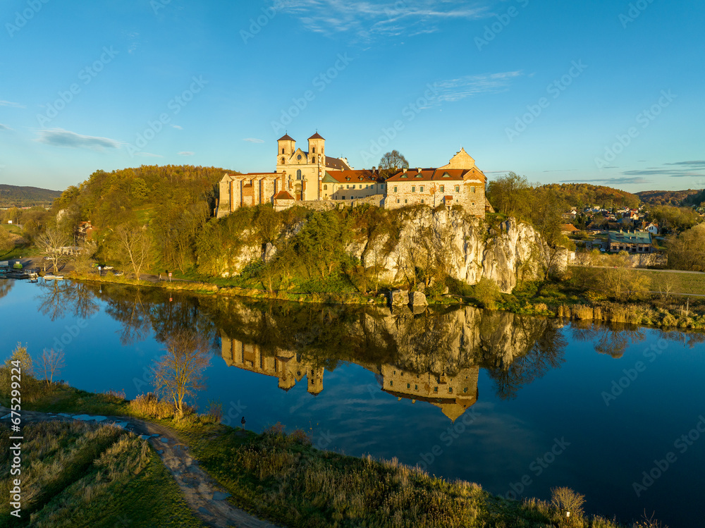 Tyniec near Krakow, Poland. Benedictine abbey and monastery on the rocky cliff and its water reflection in Vistula River. Aerial view in autumn in sunset light