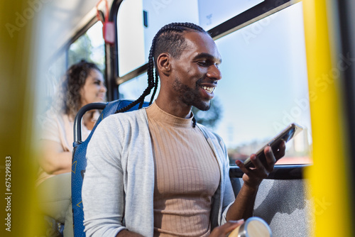 Jovem negro usando smartphone durante uma viagem de onibus.
