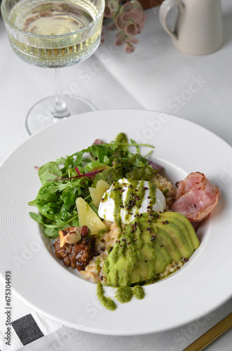 Healthy Breakfast Bowl with Oatmeal, Poached Egg, Salad and Avocado