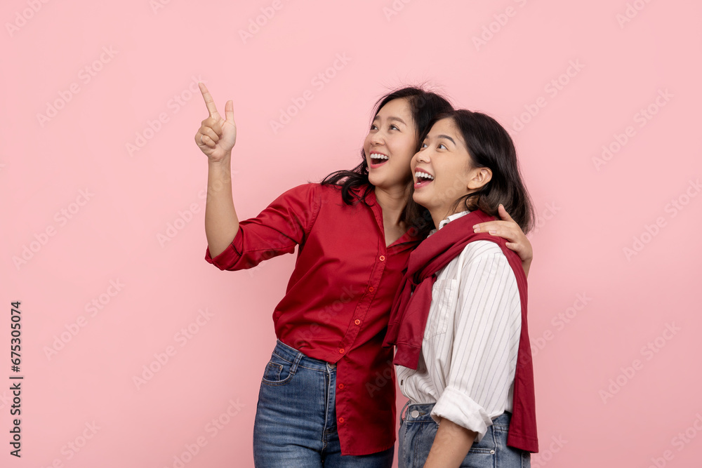 Beautiful Asian woman in red shirt pointing to send message isolated Attractive and cheerful Asian women hugging each other on pink background. Beautiful Asian woman in red shirt pointing to send message isolated Attractive and cheerful Asian women hugging each other on pink background.
