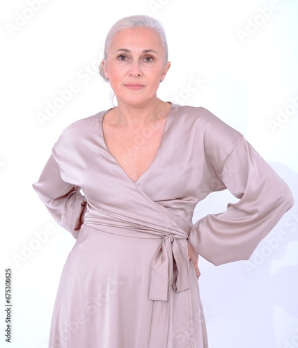 Beautiful aging adult woman in silk dress on white background