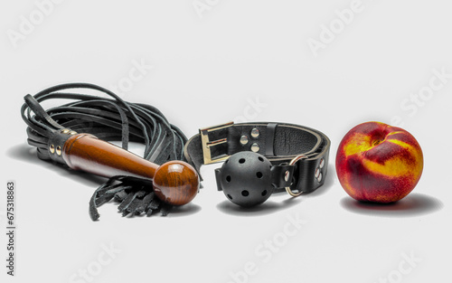 bdsm leather black gag whip and ripe peach fruit on white background photo