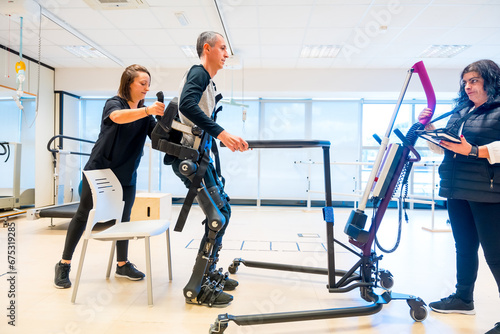 Mechanical exoskeleton. Physiotherapy medical assistant lifting disabled person with robotic skeleton to get up. Futuristic rehabilitation, Physiotherapy in a modern hospital