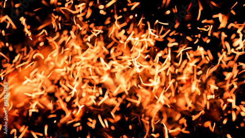 Fire embers particles over black background, blur bokeh effect. Fire sparks background. Abstract dark glitter fire particles lights. bonfire in motion blur.