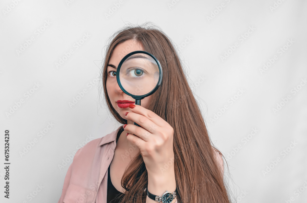 Close up of young brunette woman looking through magnifying glass, isolated over white background Close up of young brunette woman looking through magnifying glass, isolated over white background