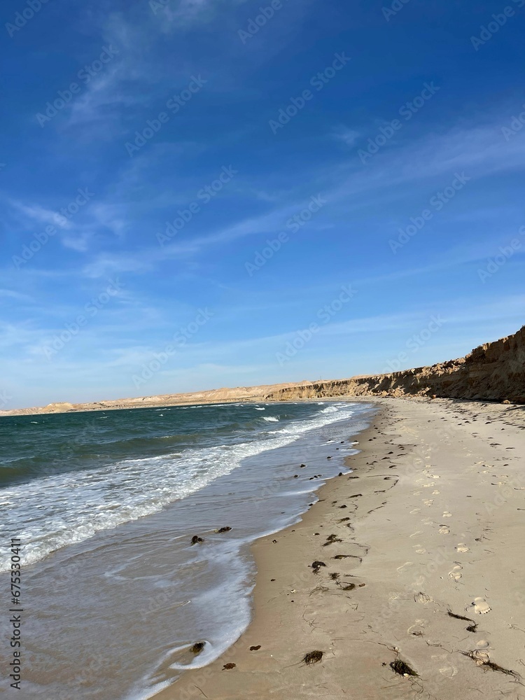 Vertical of sandy Dakhla beach against the sea waves on a sunny day