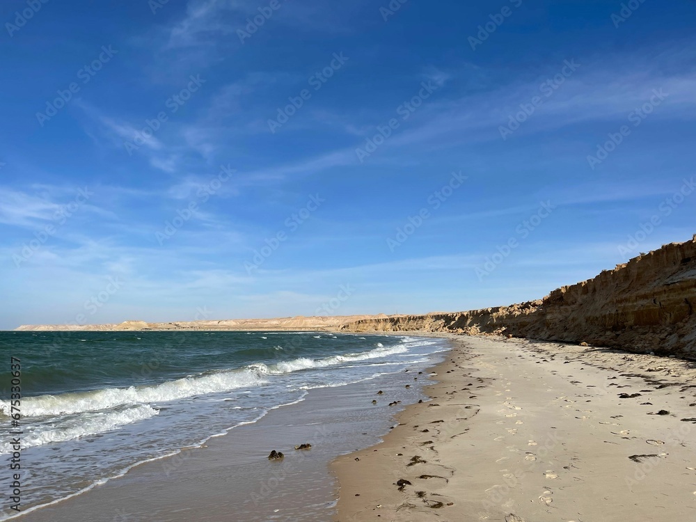 Scenic view of sandy Dakhla beach against the sea waves on a sunny day