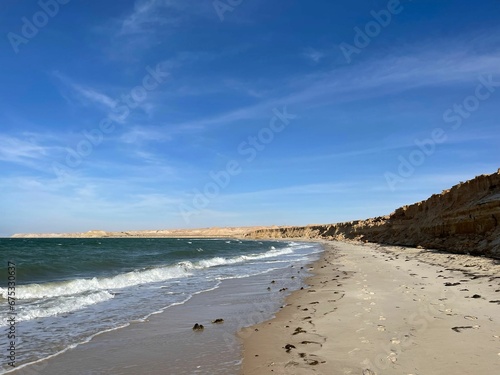 Scenic view of sandy Dakhla beach against the sea waves on a sunny day