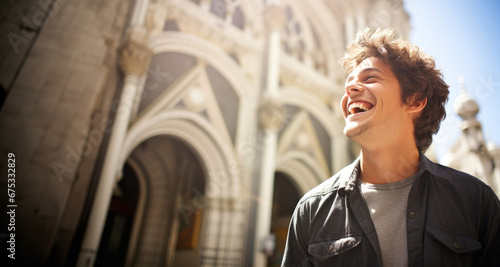 Hombre Joven Turista sonriente de pie delante de una catedral photo