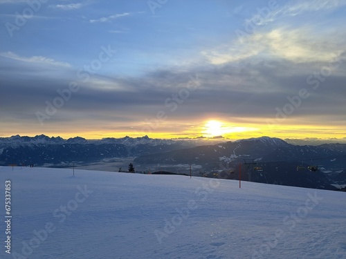 Beautiful snow-covered ski slope illuminated by warm sunset light with majestic mountain peaks © Wirestock