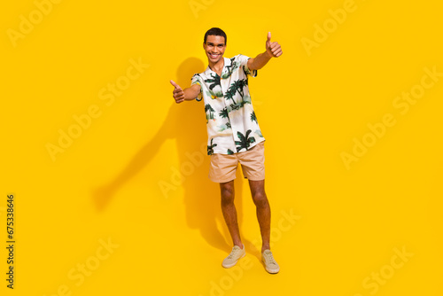 Full length photo of nice young male showing thumb up good quality wear trendy palms print garment isolated on yellow color background