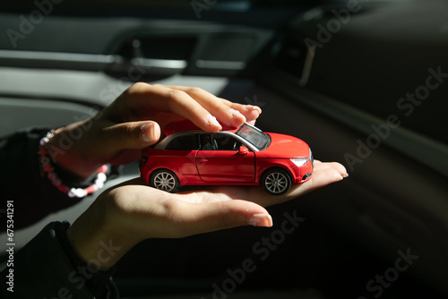 Caucasian female hand showing red toy car.