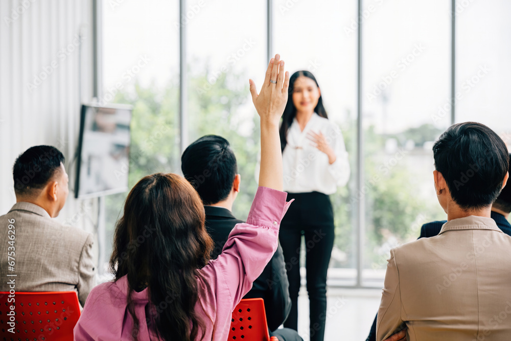 Obraz premium A large group in a seminar classroom raises their hands, actively participating and engaged in the discussion. The audience has the answer in this dynamic conference setting.