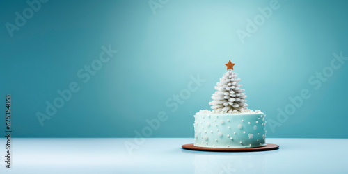 On a light blue background there is a Christmas cake decorated in the form of a Christmas tree. Minimalism. 