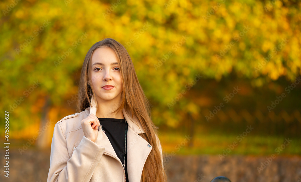 A young smiling girl walking in an autumn park in a good mood. Teenage girl, portrait against a background of nature. Fashion style trend. A young smiling girl walking in an autumn park in a good mood. Teenage girl, portrait against a background of nature. Fashion style trend.