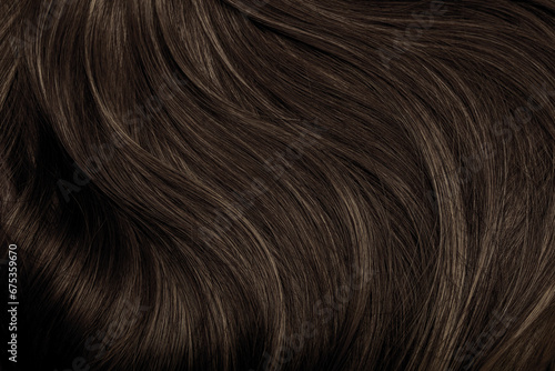 Brown hair close-up as a background. Women's long brown hair. Beautifully styled wavy shiny curls. Hair coloring. Hairdressing procedures, extension.