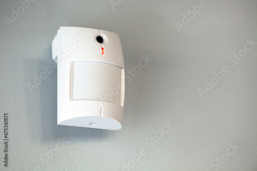 A white motion sensor camera on a gray wall, providing security and surveillance. photo