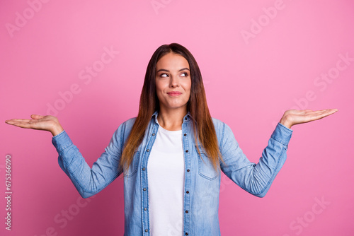 Portrait of nice curious cheery brown-haired girl holding on palms copy space choosing options isolated over pastel color background