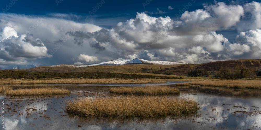 Stunning view of a marsh with a mountain range, and beautiful low clouds floating in the background.