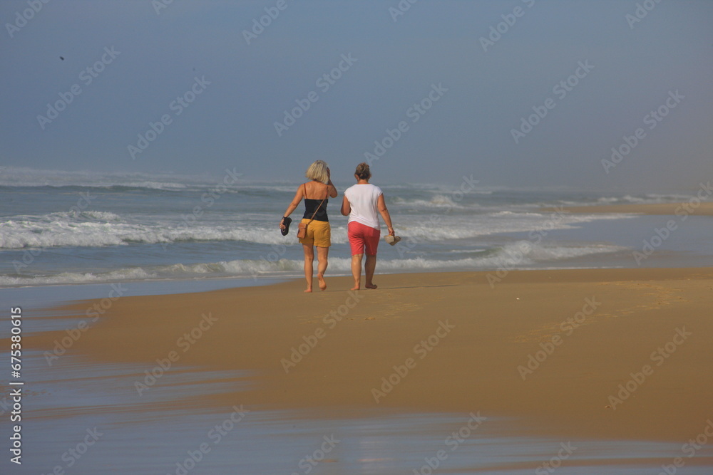 Φωτογραφία Zwei Frauen gehen an einem schönen sonnigem Tag am Meer spazieren