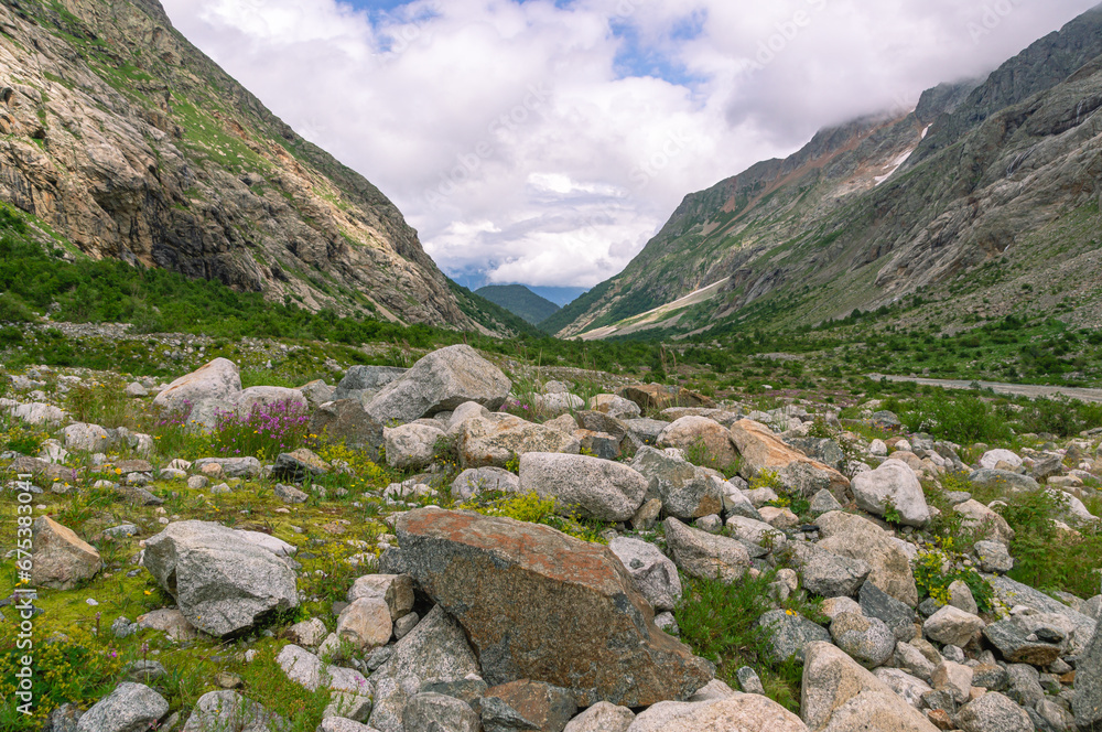 Fototapeta premium Panorama of a gorge in a mountainous area. Granite stones in the mountains. Landscape in summer with views of mountains, clouds and flowers. Hiking in the mountains. A trip to the mountains.