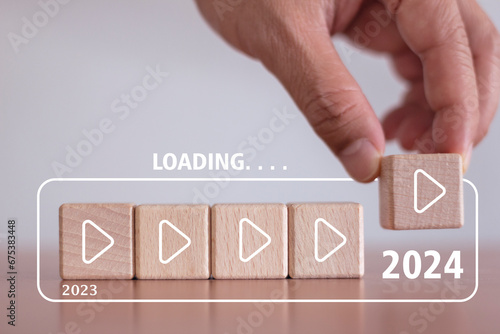 Loading countdown to the new year 2024. Hand holds loading bar on wooden block, year 2023 to 2024, starting point of initial goals and action plan concept. photo