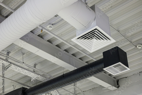 Two ventilation duct systems with grilles under ceiling in commercial building. Supply and exhaust photo