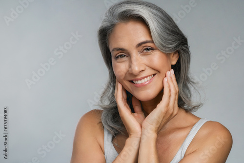 Close-up portrait of a mature woman with beautiful well-groomed skin, posing with her hand close to her face. photo