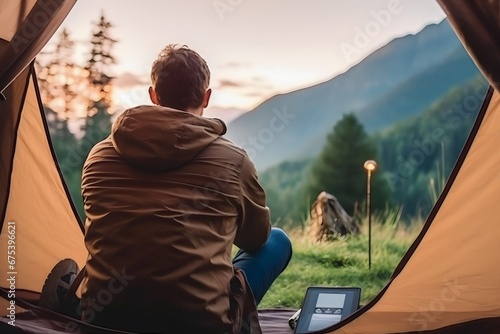 Male traveler camping on the mountain while playing on his phone photo