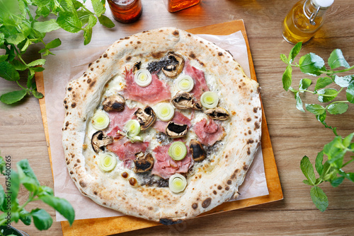 White pizza with leek, mushrooms, ham and cheese, on a wooden cutting board, top view.