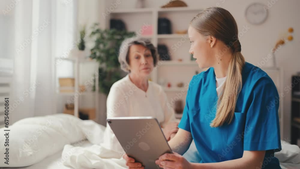 Female doctor explaining test results on tablet to senior woman in hospital bed Female doctor explaining test results on tablet to senior woman in hospital bed