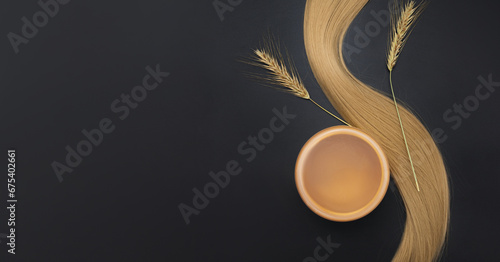 Blond long hair with cream jar and sprigs of ripe wheat. Healthy hair. Black background. Hair tools, beauty and hairdressing concept. Hair care, healthy hair photo