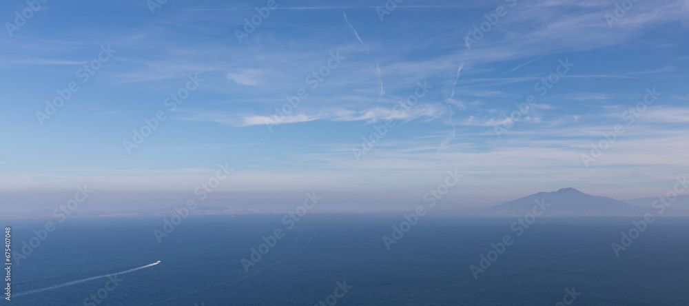 bateau avec sillage sur la mer avec au loin une île dans la brume bateau avec sillage sur la mer avec au loin une île dans la brume