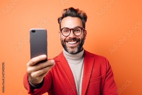 happy man taking selfie on smartphone on orange background photo