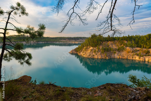 A lake with turquoise water on a sunny summer day with clouds in the sky © Vadim Volodin